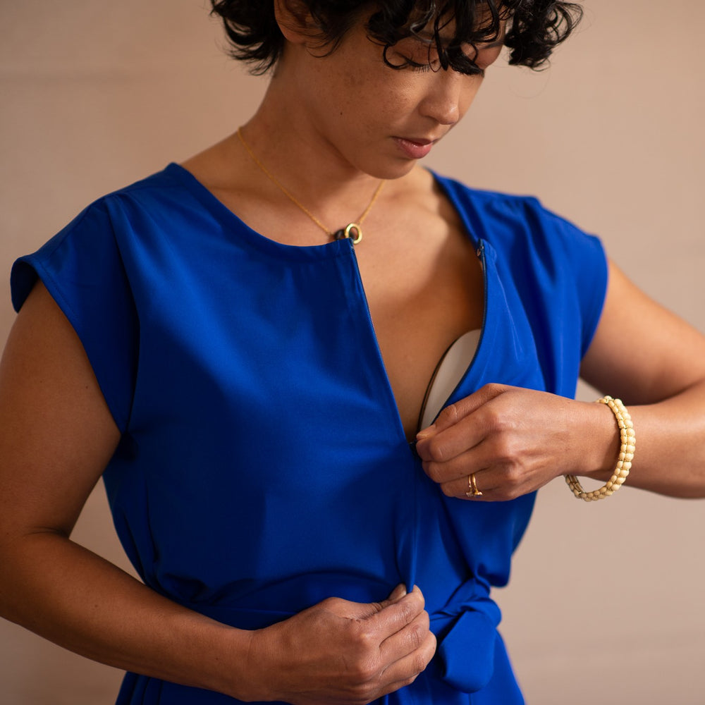 Woman zipping a Fulcrum Apparel dress while wearing a wearable breast pump