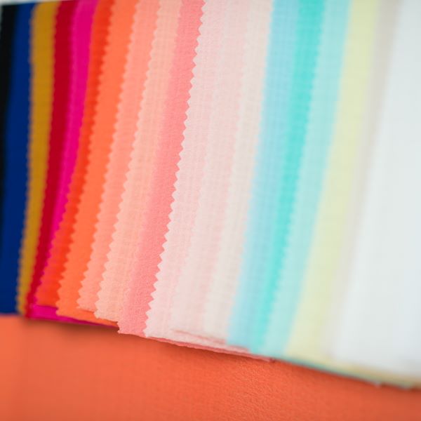 Various colors and types of fabrics draped on a white background