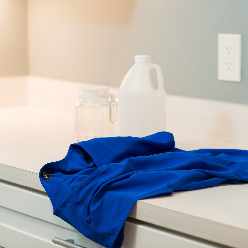 Fulcrum Apparel pumping blouse and detergent on counter in a laundry room